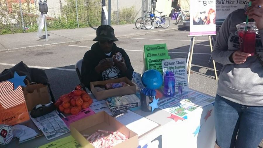 Bellingham United's Mo Mareneh checks scores between talking with fans on Saturday at the Bellingham Farmer's Market. (BUFC Black & White Army photo)